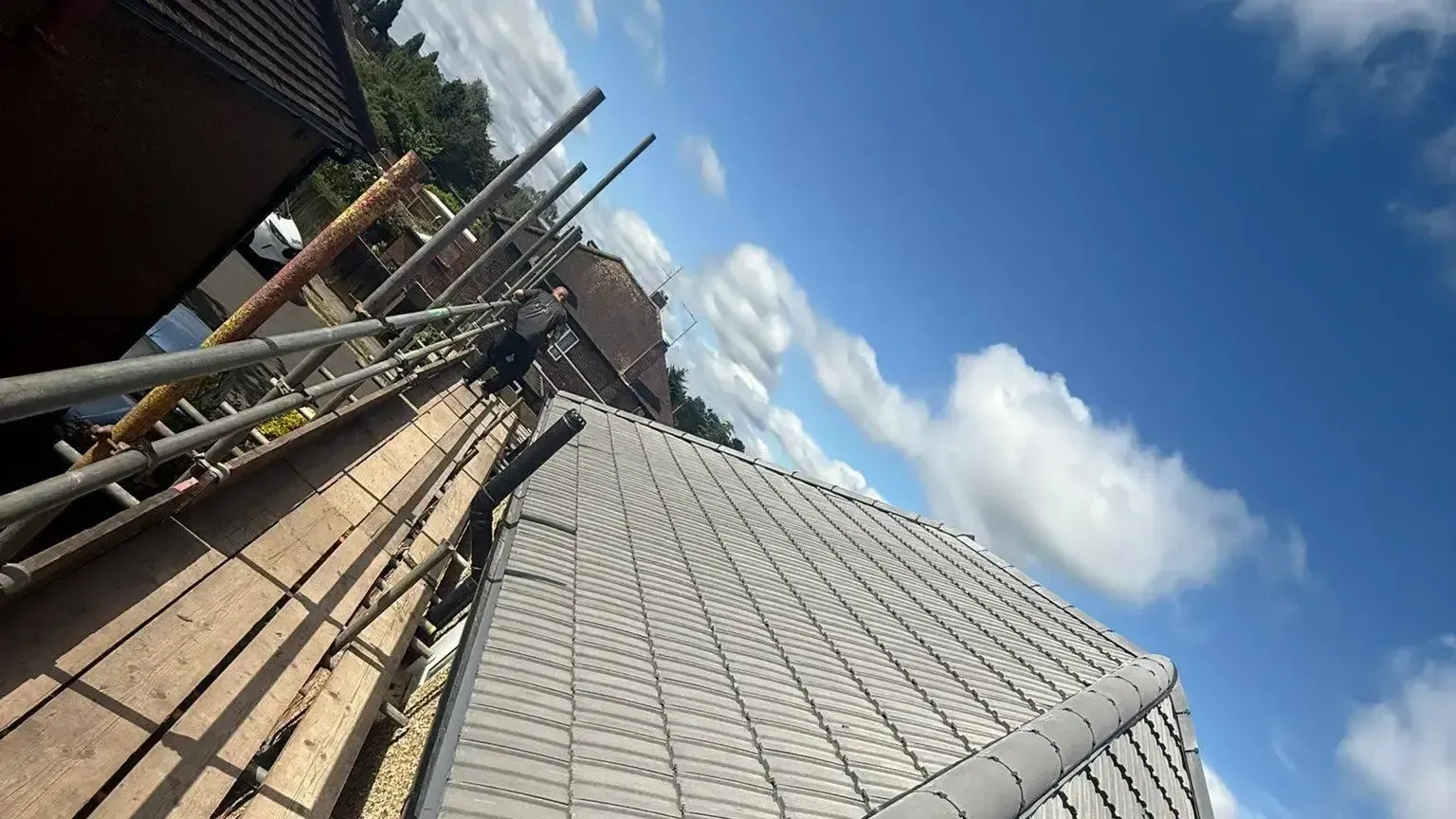 A-List Roofing roofer completing a new tiled roof on a scaffolded property in Surrey